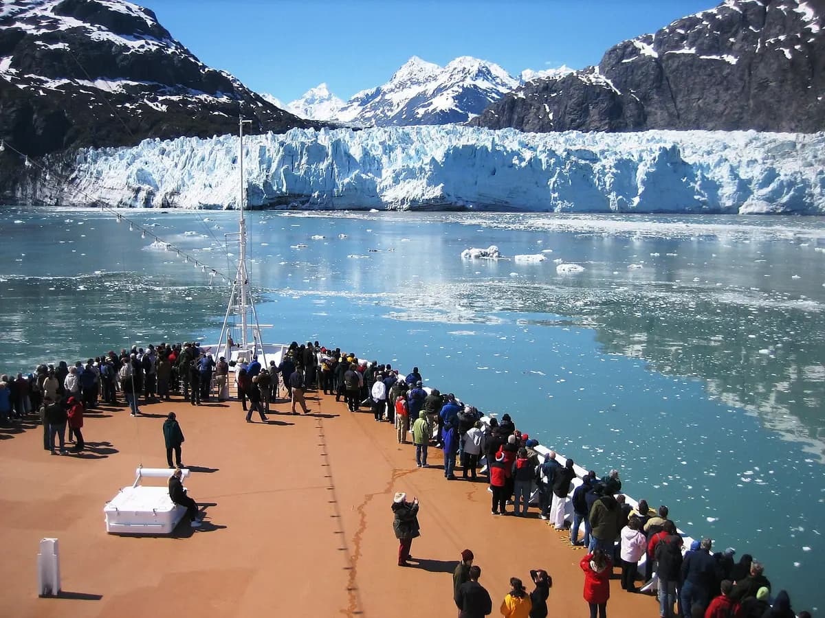Passengers on the bow of a cruise ship facing a glacier in Glacier Bay, Alaska
